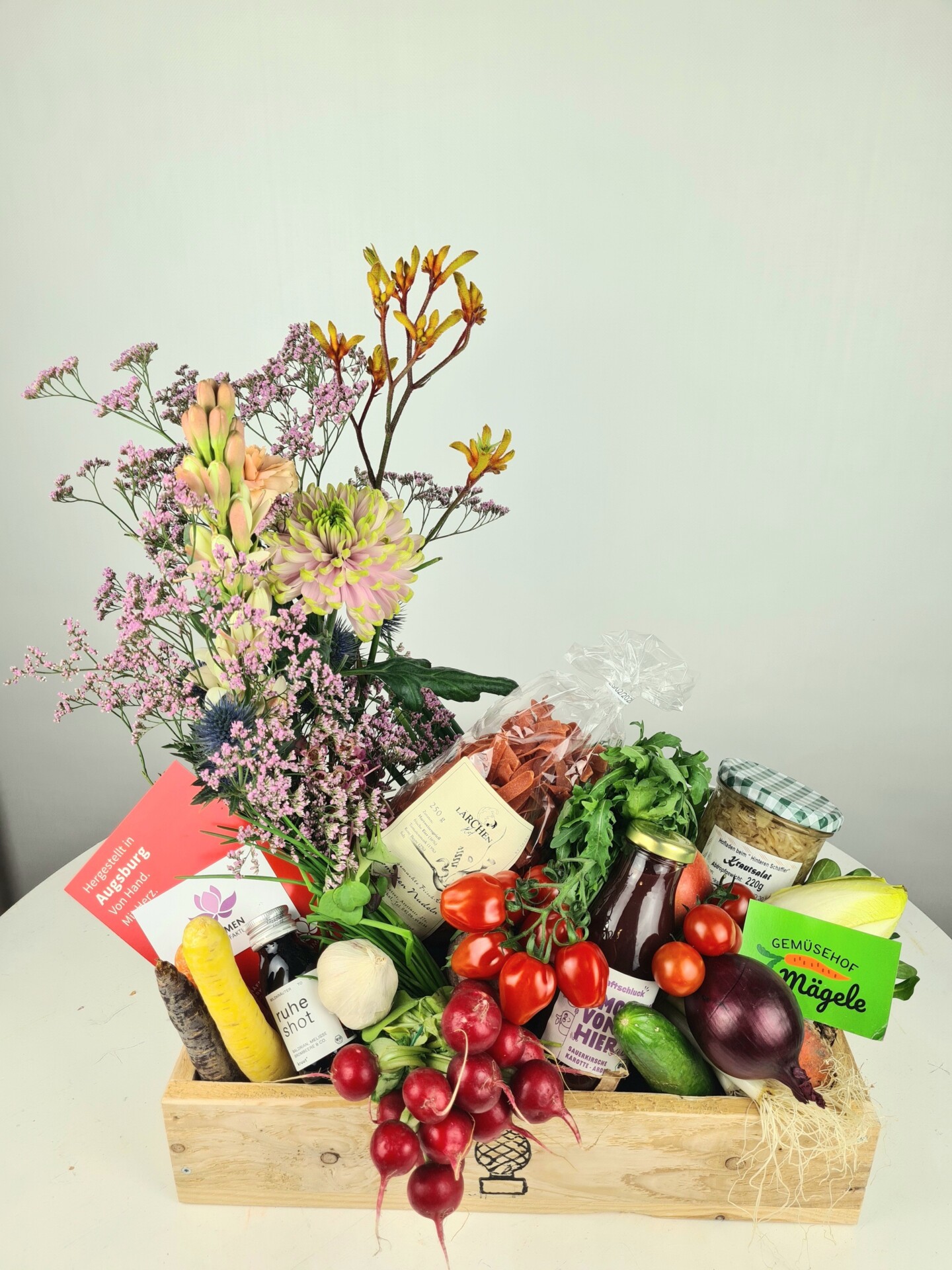 Gefüllte Holzkiste mit Gemüse, Pasta und Blumen