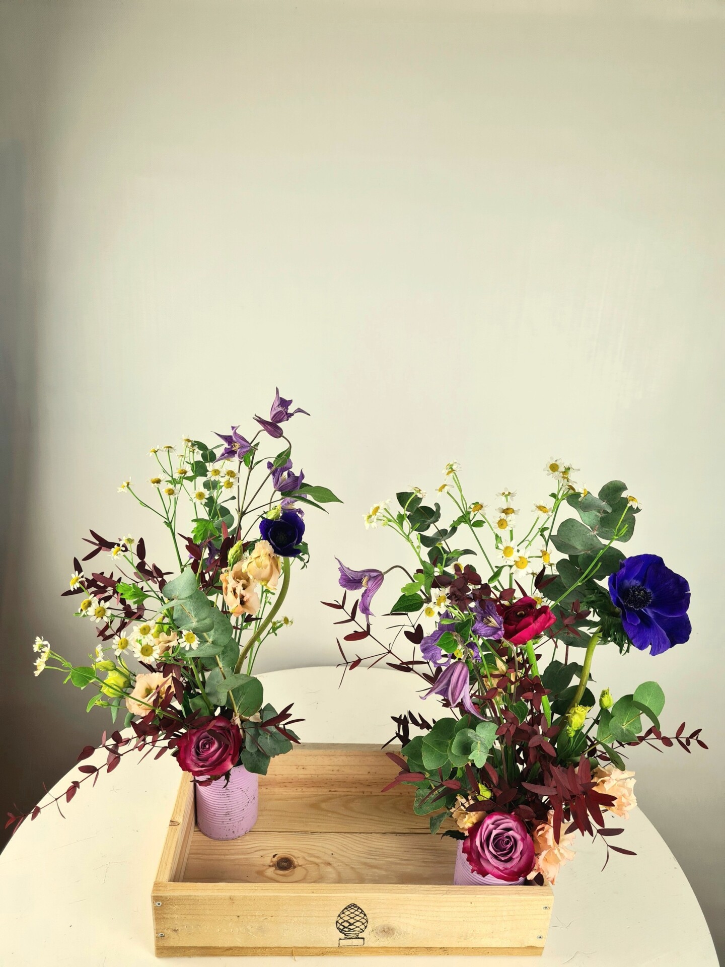 Zwei bunte Blumenarrangements in Holztablett