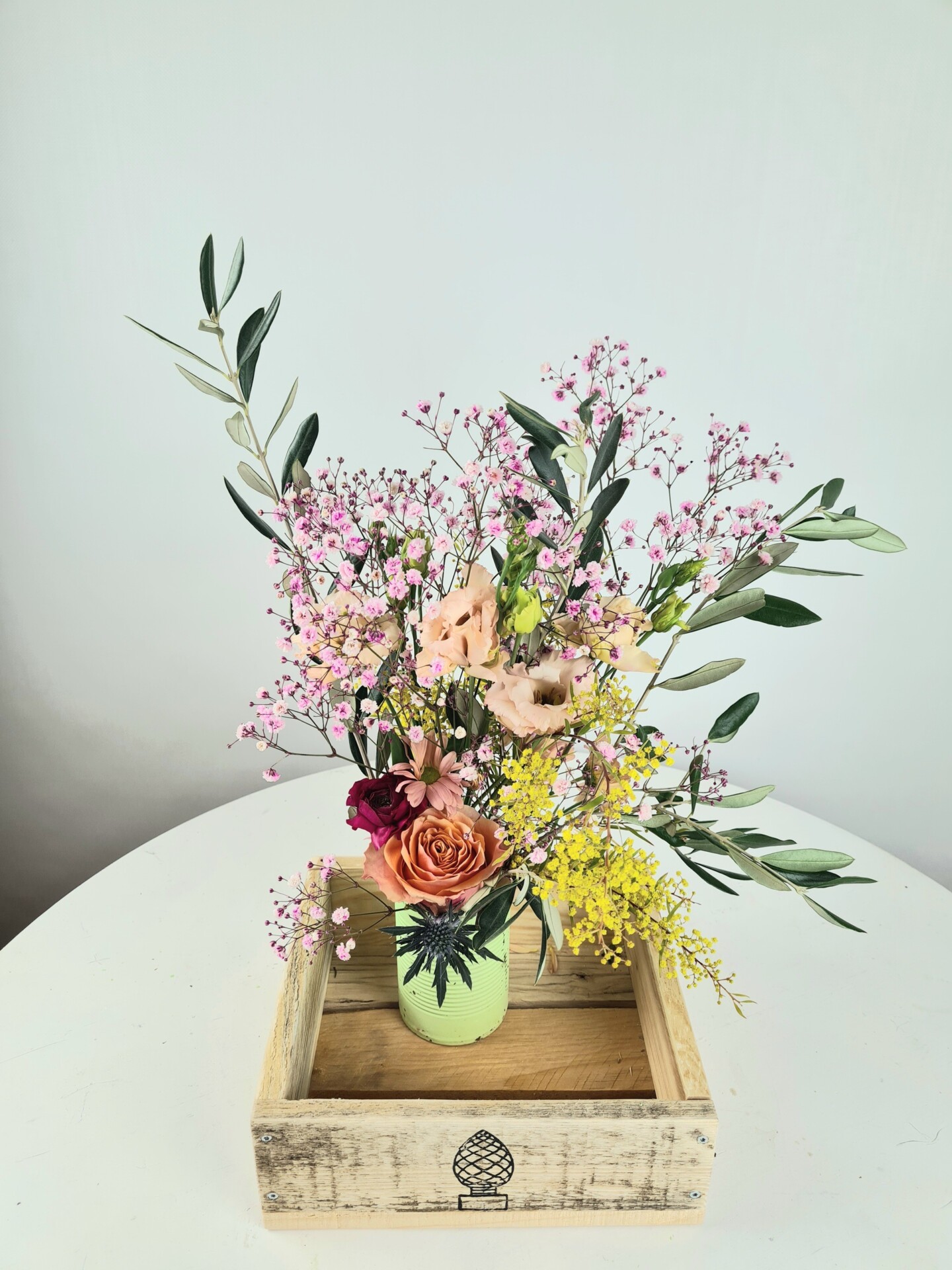 Bunter Blumenstrauß in Holzbox auf weißem Tisch