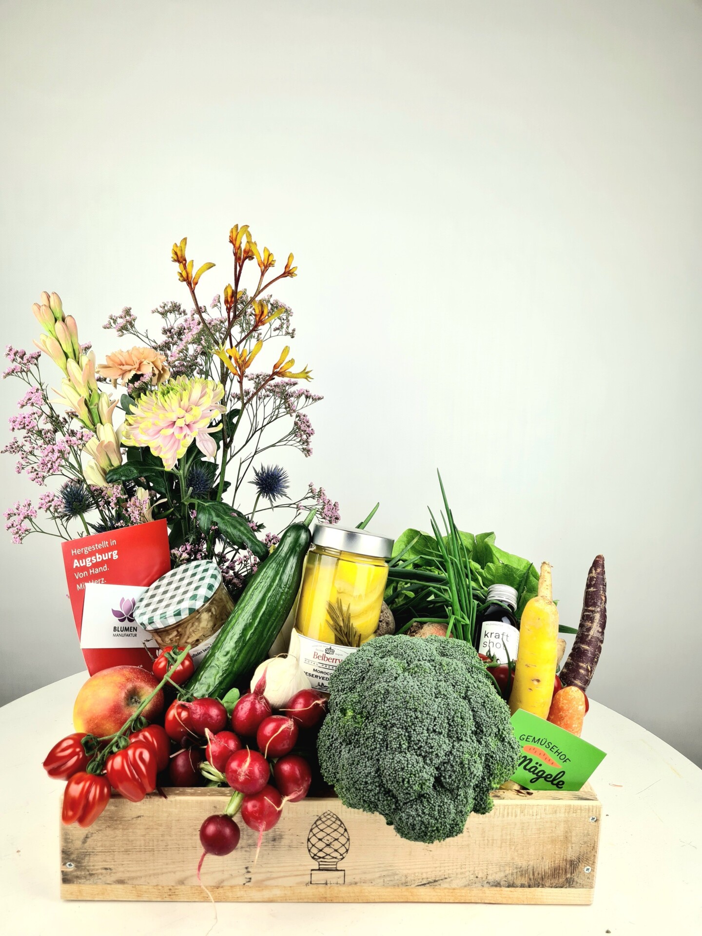 Holzkiste mit Gemüse, Blumen und regionalen Produkten